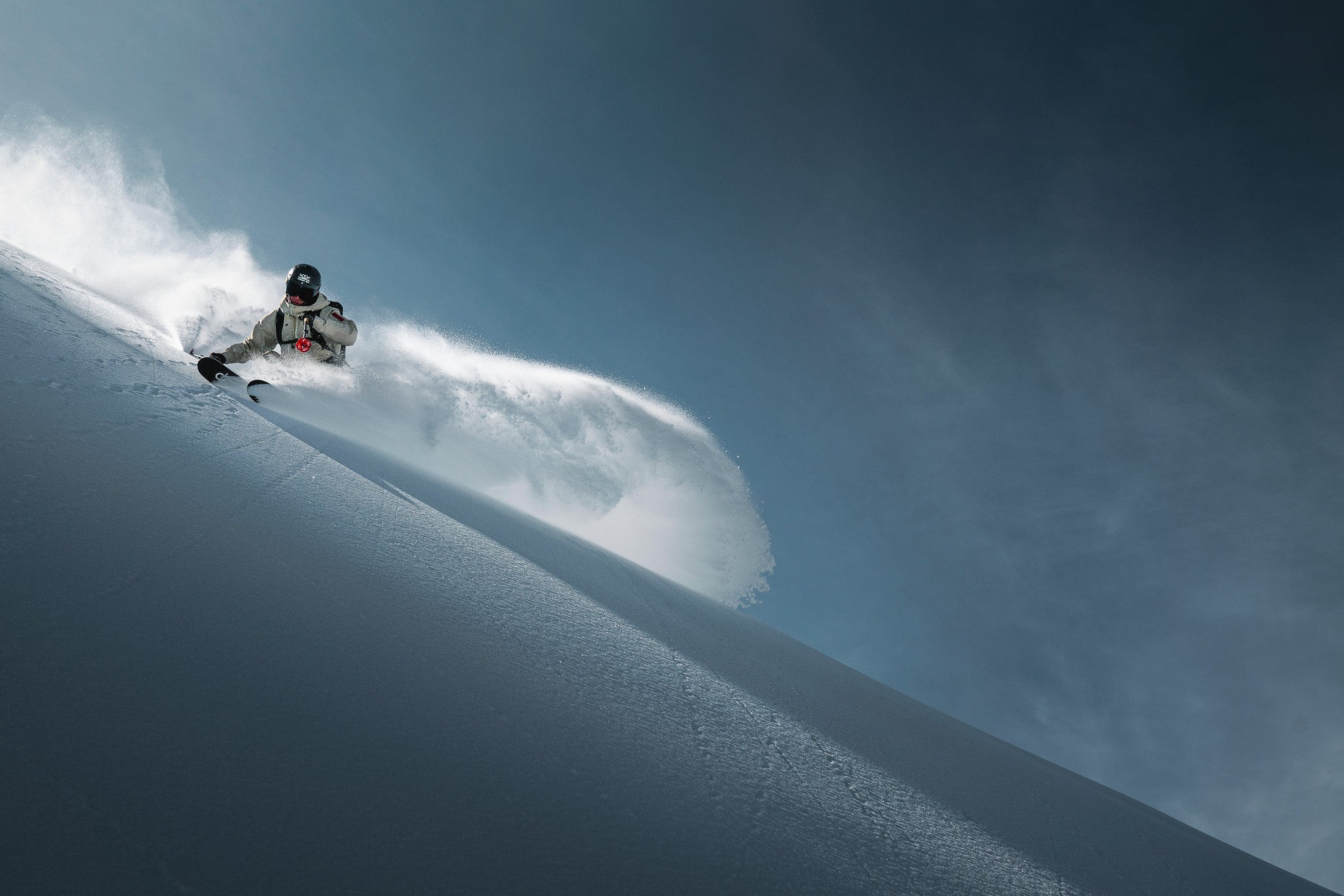 DPS Lotus powder skis floating in deep snow, rider in motion in Utah mountains, lightweight carbon performance.